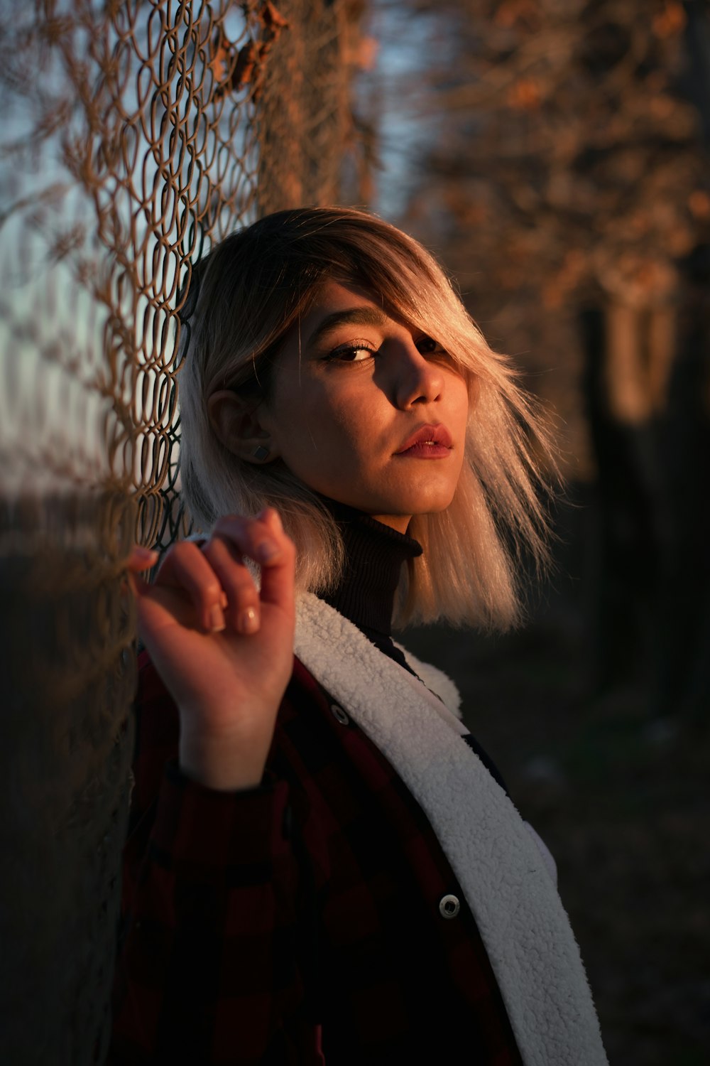 woman in gray coat leaning on gray metal fence during daytime