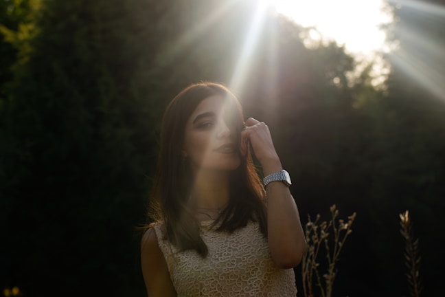 A woman wearing a brown earth-toned oneset standing in a sunlit natural setting