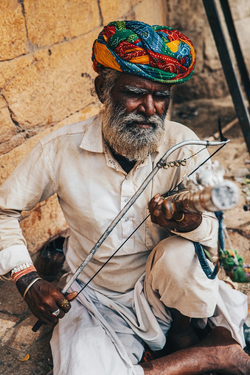 man in white long sleeve shirt wearing red and blue hat holding brown stick