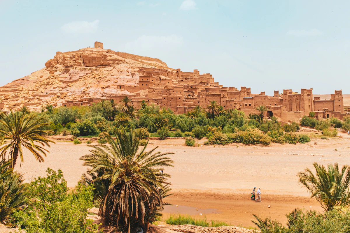Walkers on brown sand near a rock formation, Ait Ben Haddou, Morocco