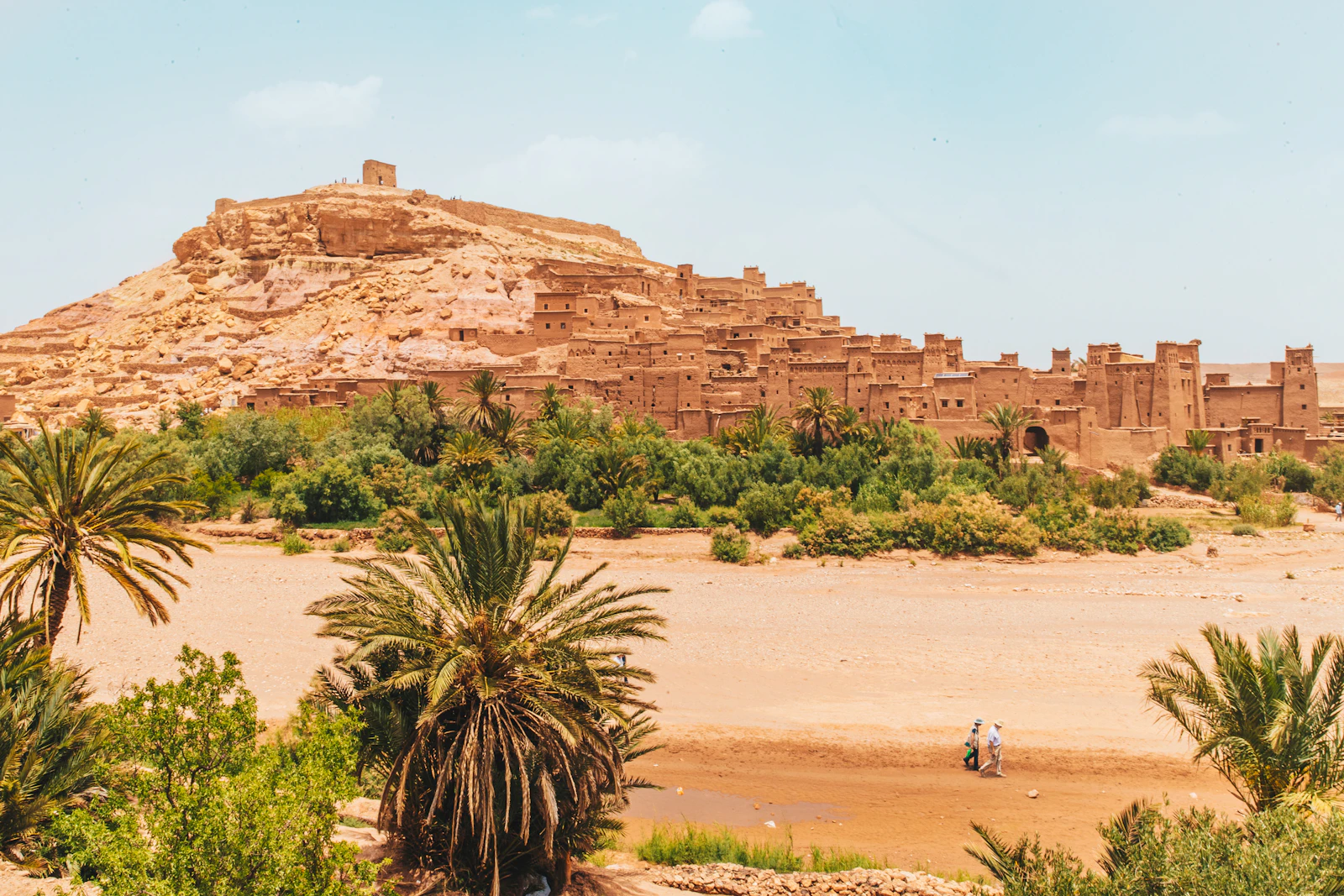 Carte routière du sud marocain dépliée sur le capot d'une voiture de location devant une kasbah en terre