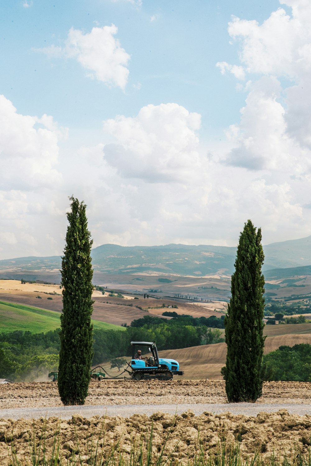 blue car on road near green grass field during daytime