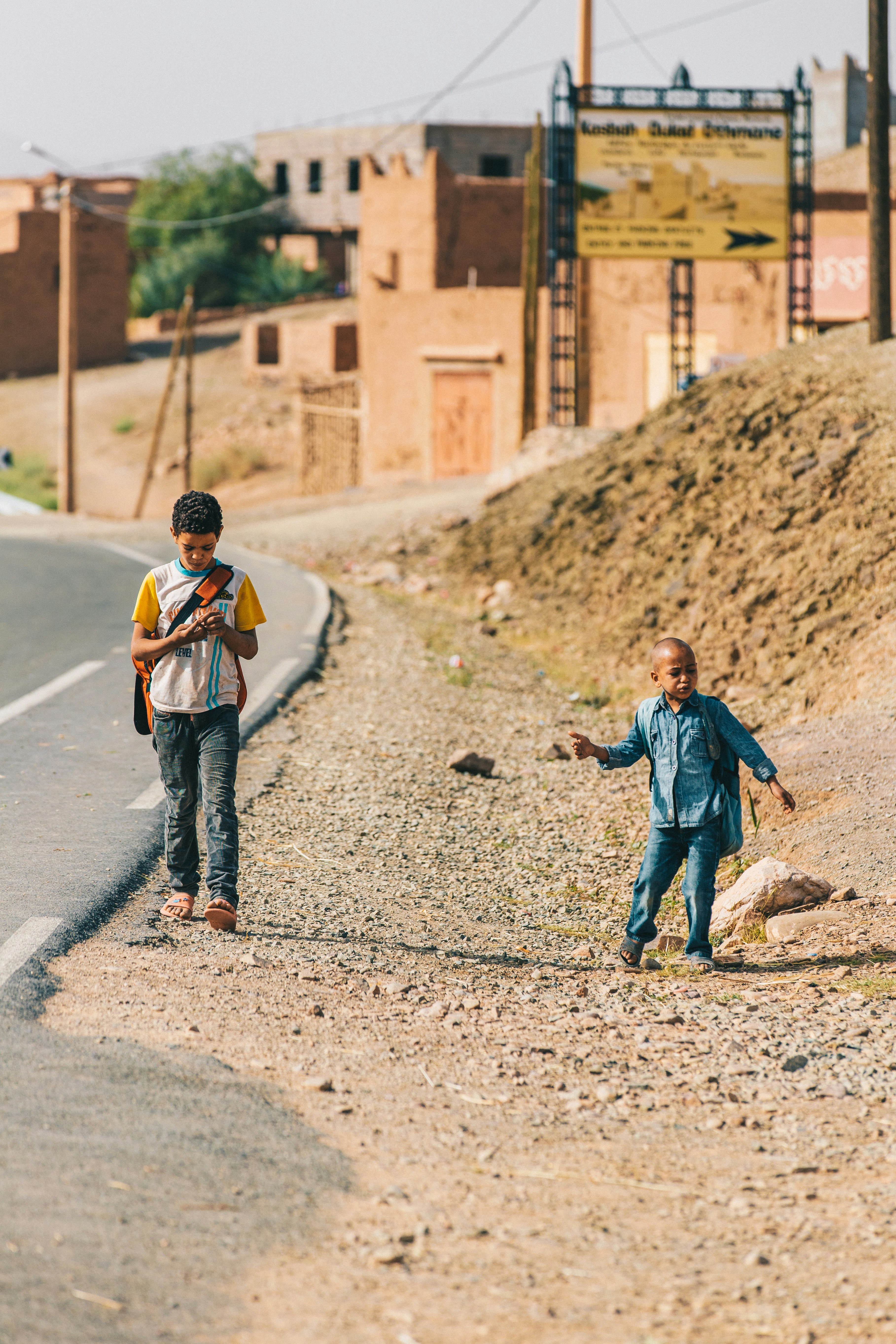 man in blue denim jacket and blue denim jeans walking on road during daytime