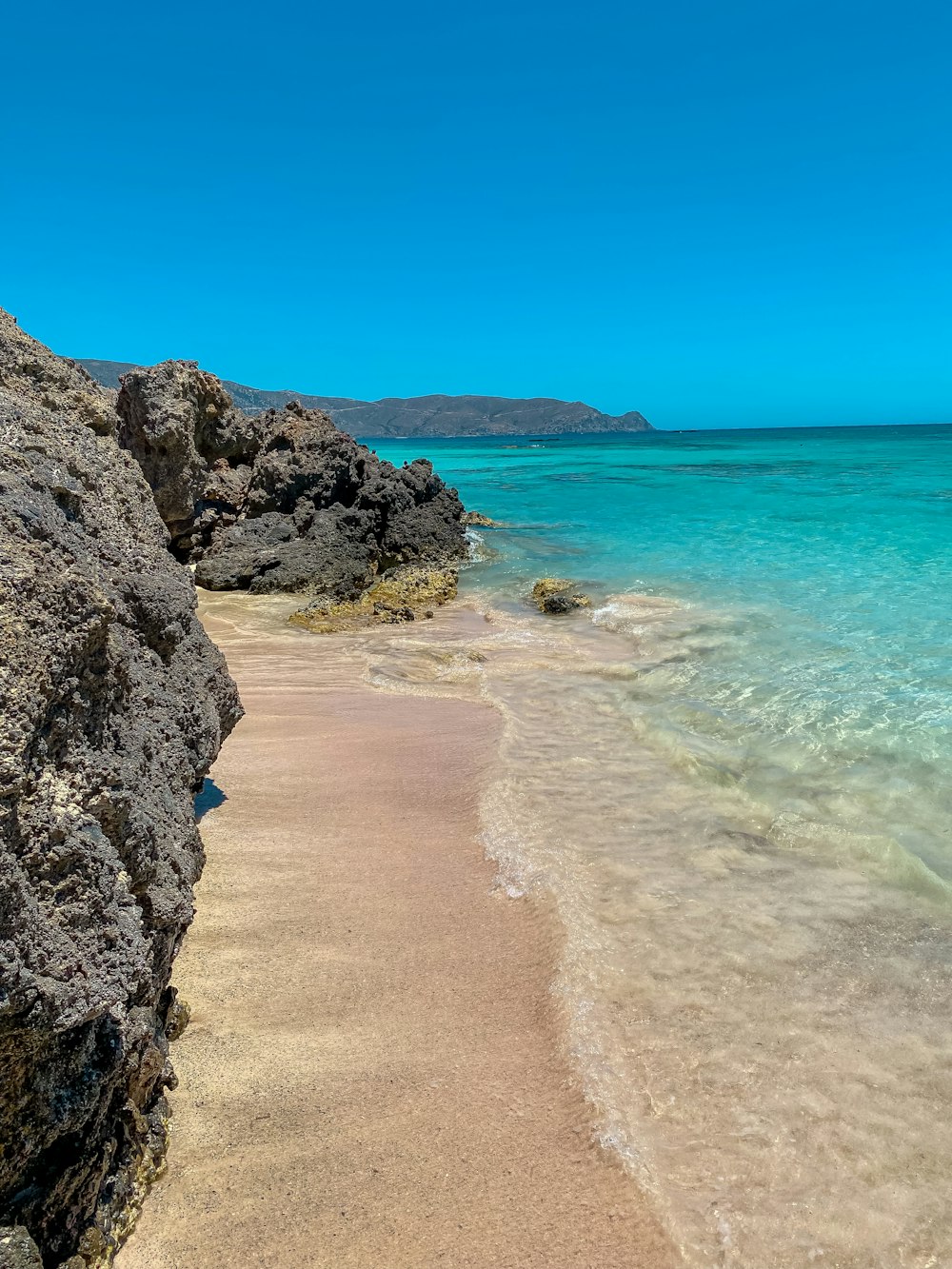 brown rocky shore near blue sea under blue sky during daytime