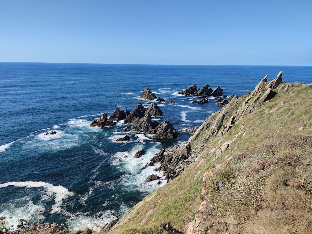 green grass covered mountain beside sea during daytime