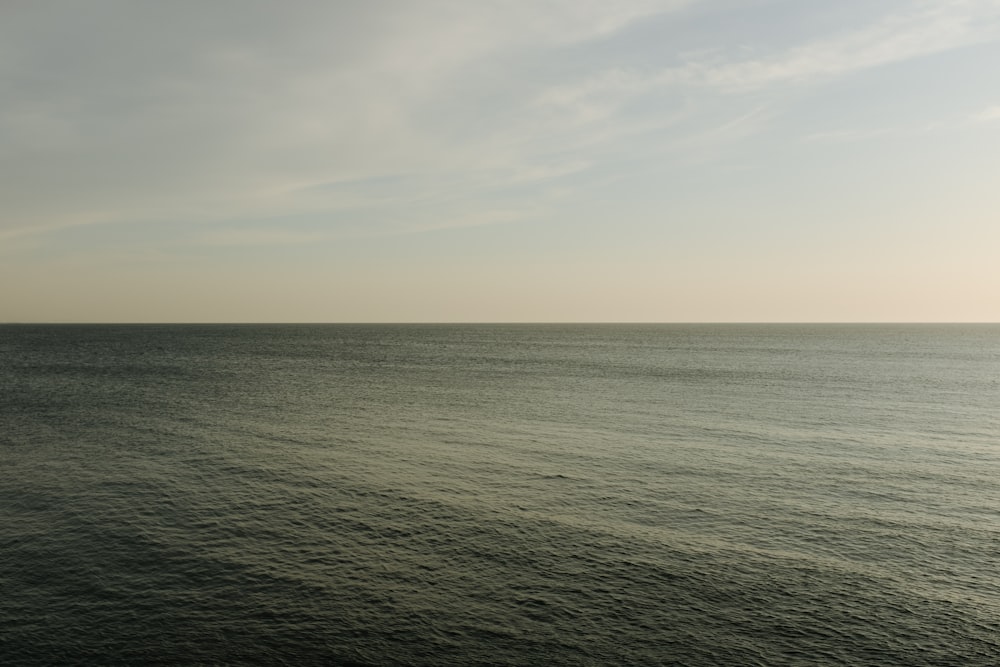 body of water under white clouds during daytime