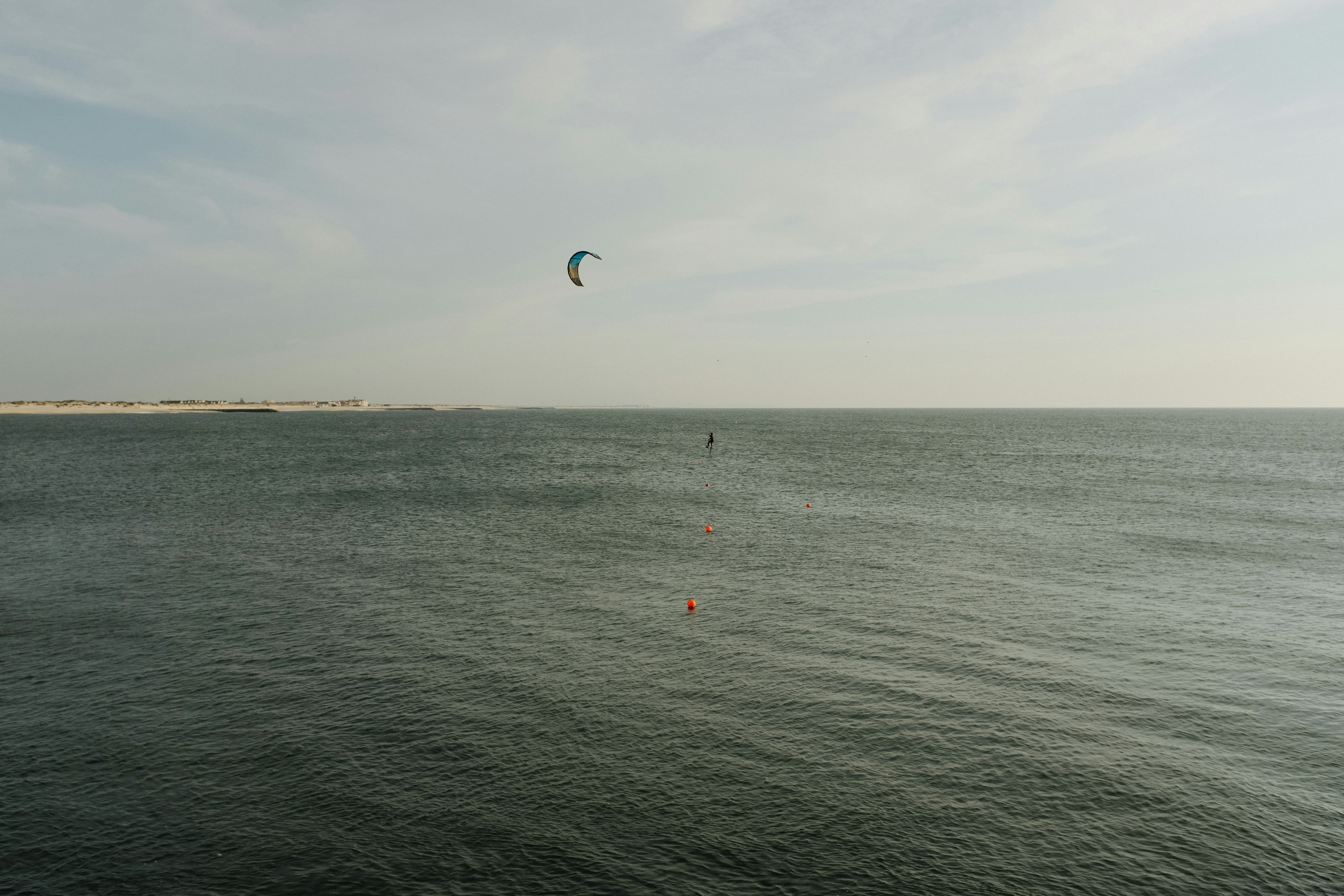 person in red and white parachute over sea during daytime
