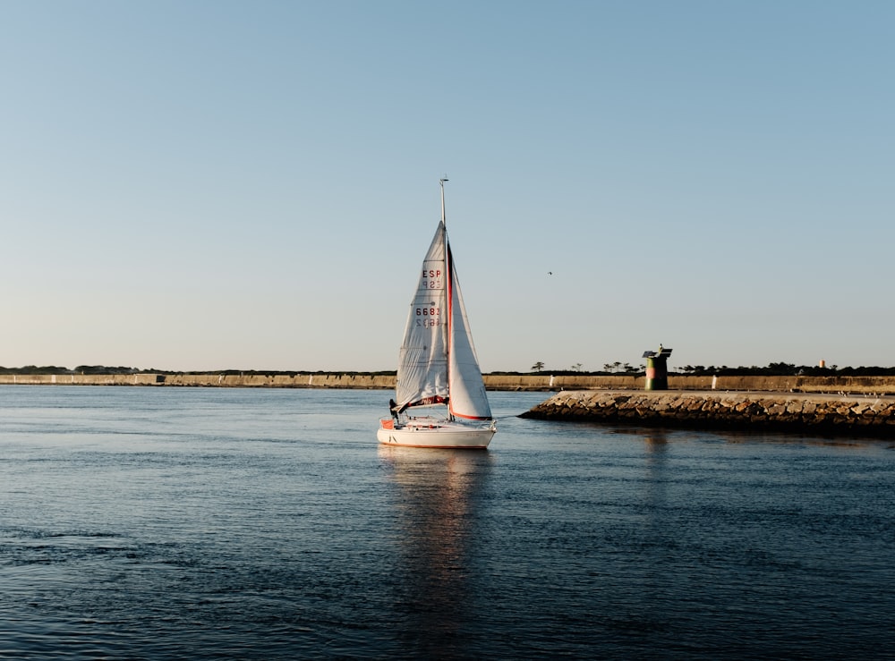 white sailboat on sea under white sky during daytime