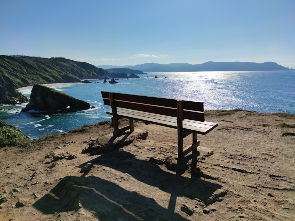 brown wooden bench on beach shore during daytime