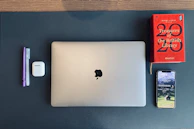 Books, headphones, and a laptop arranged neatly on a desk with Islamic geometric patterns subtly visible in the background.