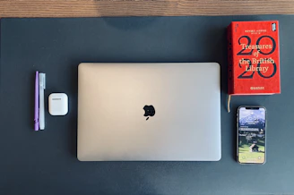 Books, headphones, and a laptop arranged neatly on a desk with Islamic geometric patterns subtly visible in the background.