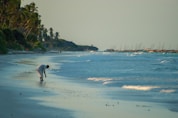 man in white shirt walking on beach during daytime