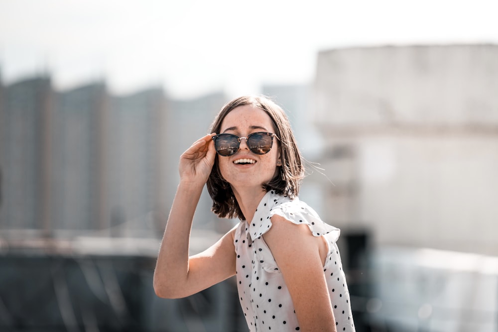 woman in white and black polka dot sleeveless shirt wearing brown sunglasses