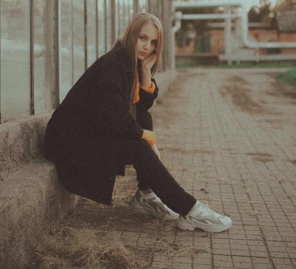 woman in black coat sitting on brown concrete bench