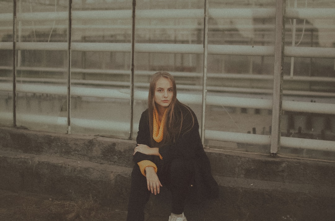 woman in black long sleeve shirt sitting on gray concrete floor