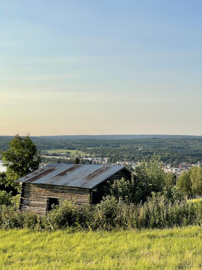 A cozy steel-frame barndominium nestled among rolling hills and limestone terrain under a clear blue Texas sky.