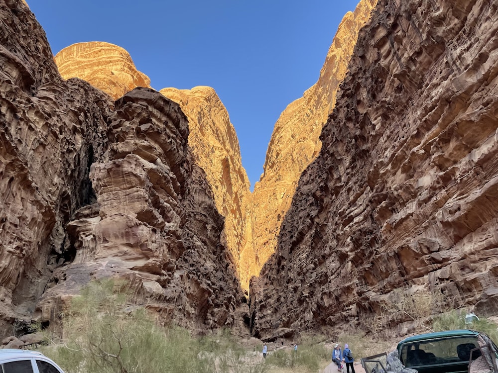 blue car in between brown rock formation during daytime