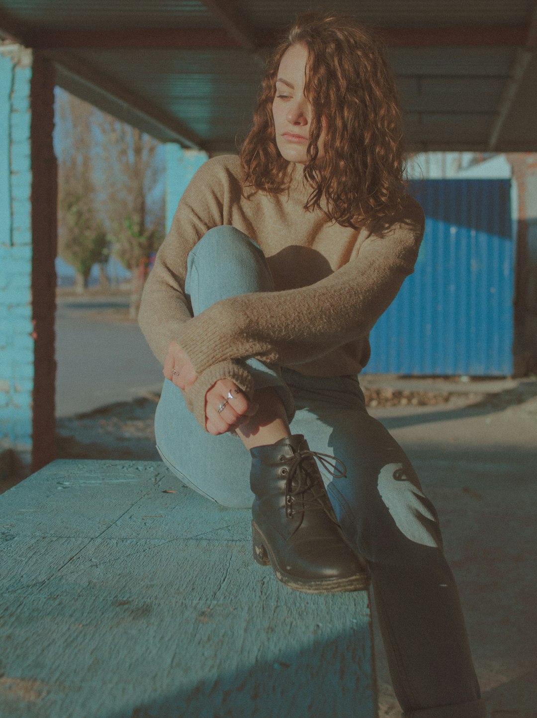 woman in gray long sleeve shirt and black pants sitting on gray concrete floor during daytime