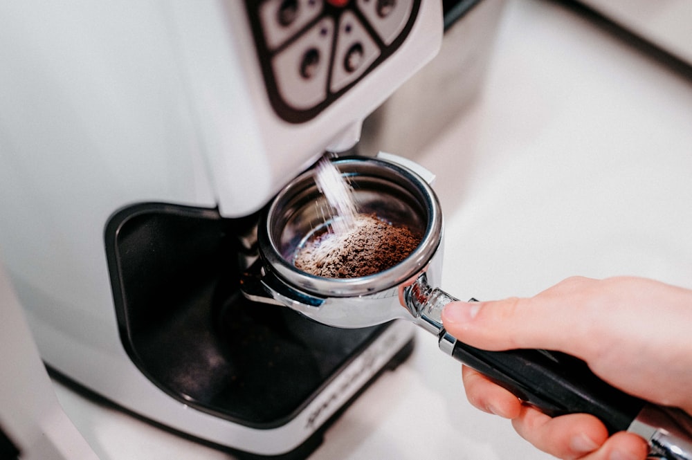 persona sosteniendo una taza de acero inoxidable con café