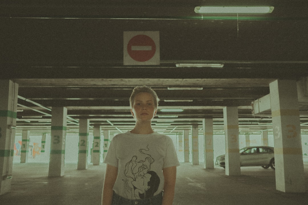 woman in white crew neck t-shirt standing near green and white building