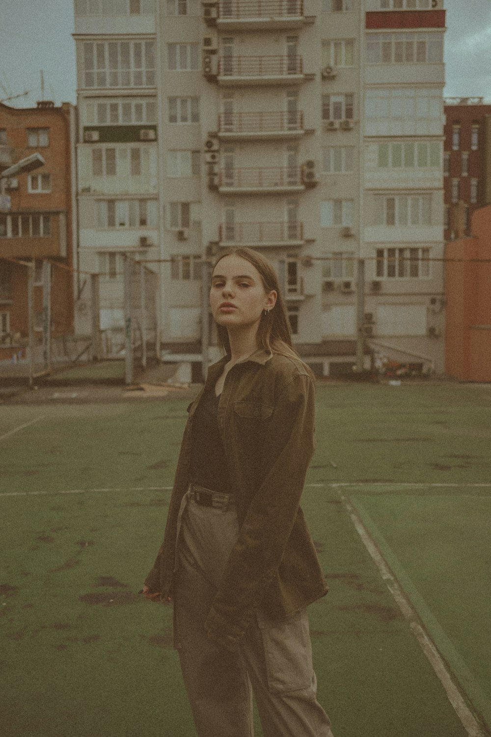 femme en manteau brun debout sur le champ d’herbe verte pendant la journée