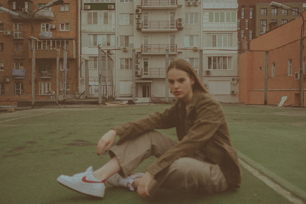 woman in brown coat sitting on green grass field during daytime