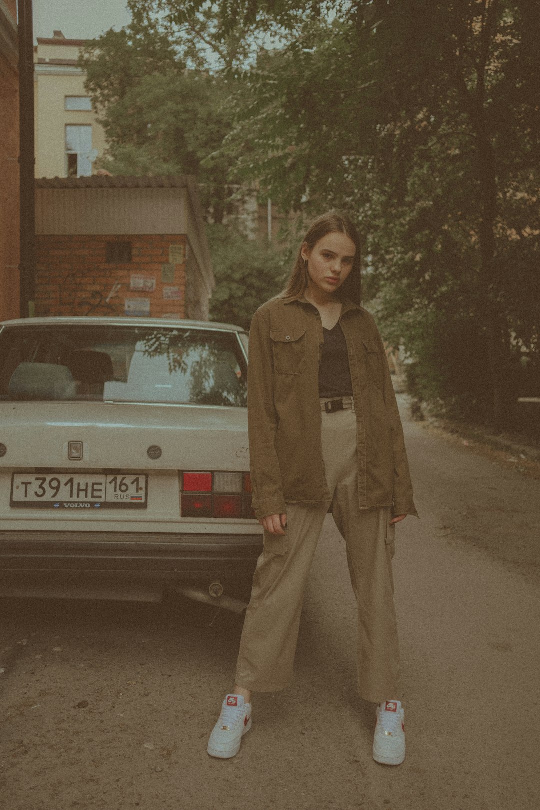 woman in brown coat standing beside white car