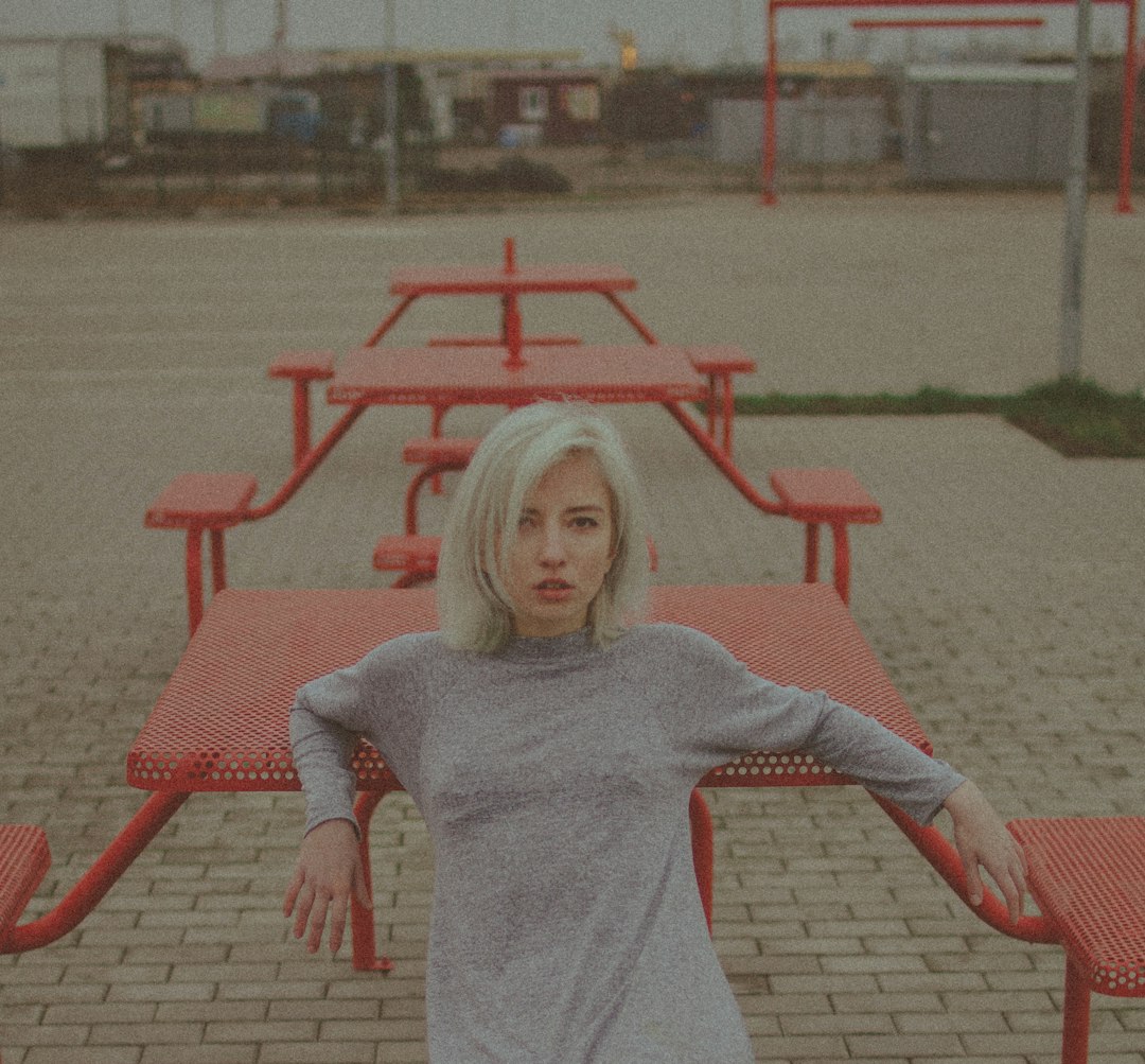 girl in gray long sleeve shirt sitting on red plastic armchair