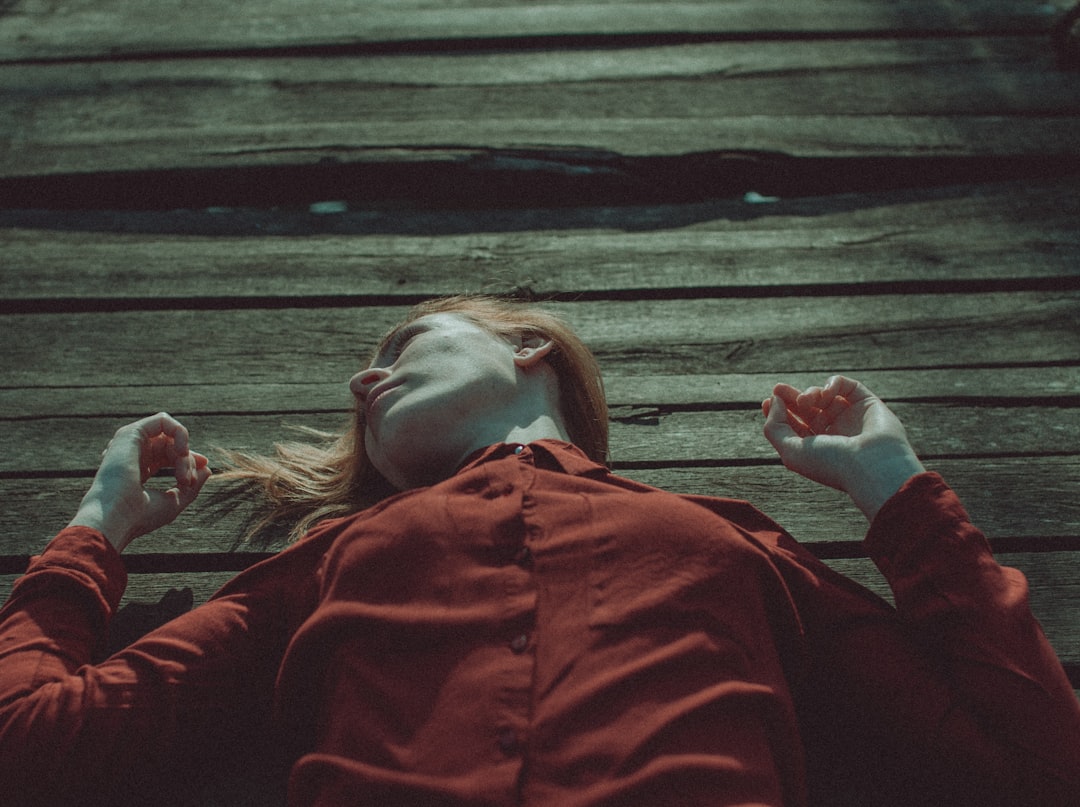 woman in red jacket lying on brown wooden floor