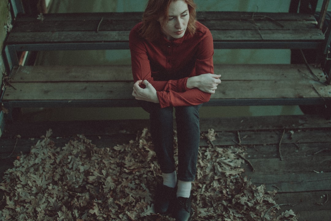 woman in red sweater and black pants standing on dried leaves