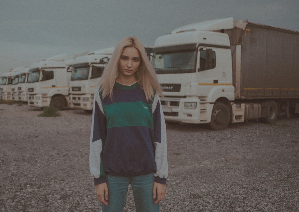 woman in white and green striped long sleeve shirt and blue denim jeans standing on gray