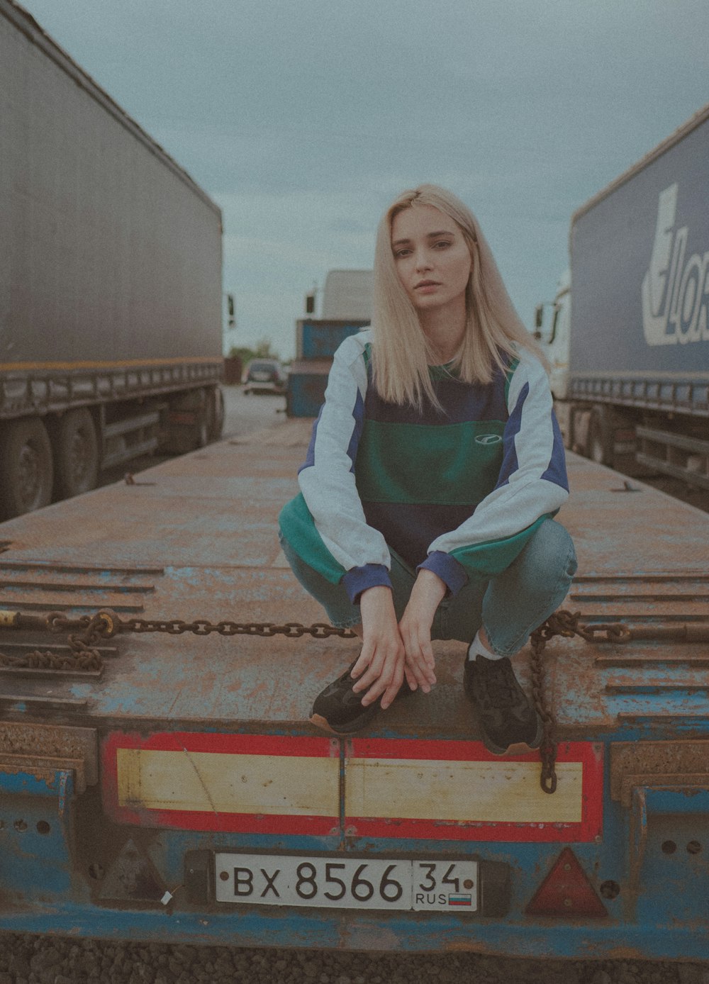 woman in blue and white jacket sitting on red metal bar during daytime