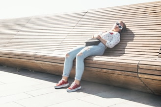 woman in white and black floral long sleeve shirt and blue denim jeans sitting on brown