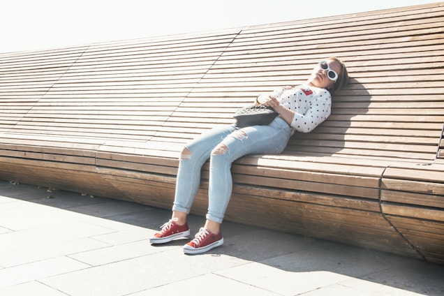 woman in white and black floral long sleeve shirt and blue denim jeans sitting on brown