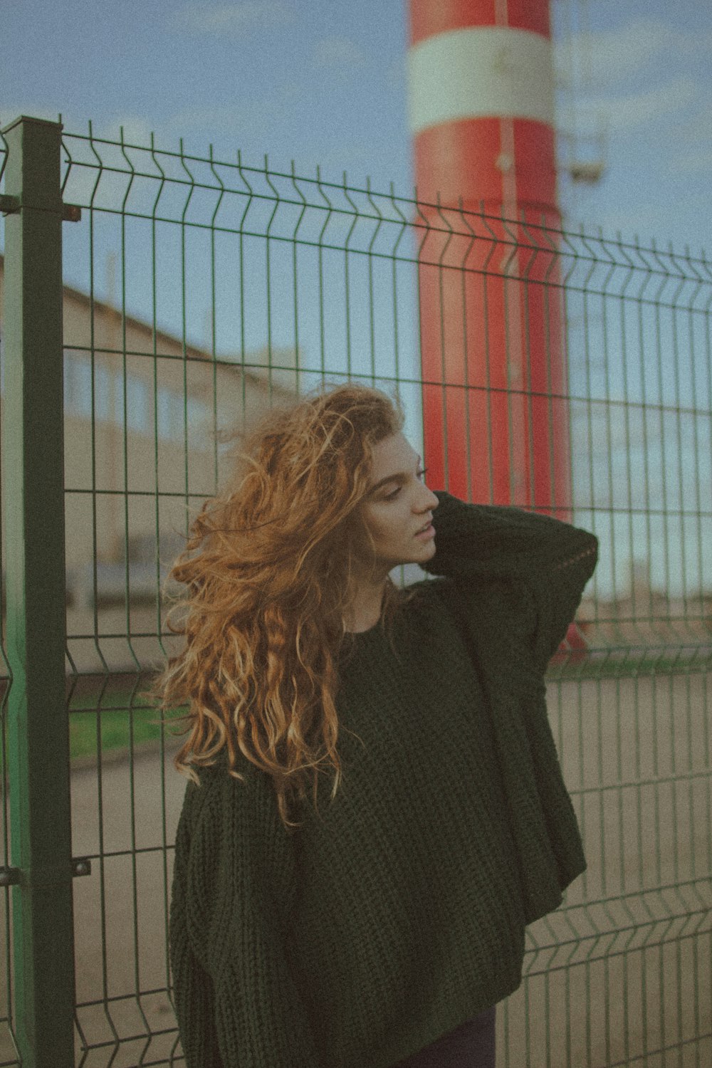 woman in black sweater standing near black metal fence