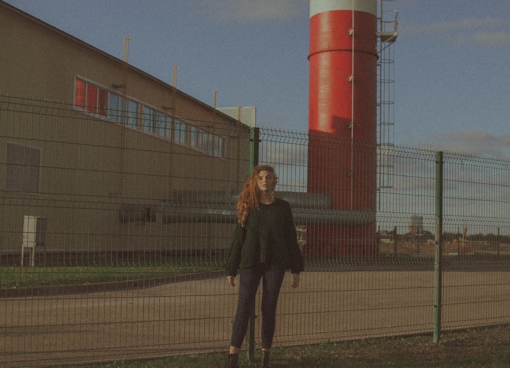 woman in black jacket standing near red and white building during daytime