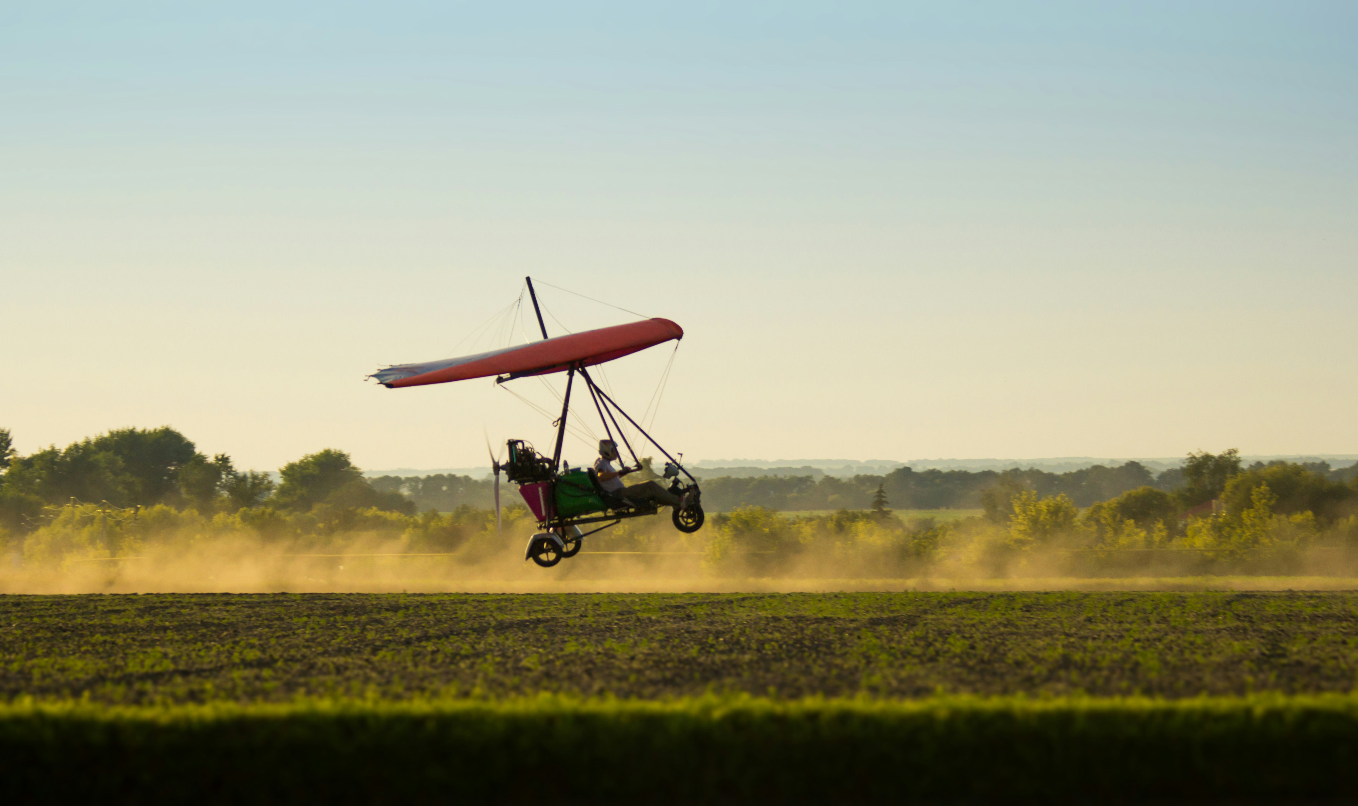 red and black drone flying over green grass field during daytime
