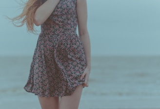 A stylish model wearing a flowing linen dress with subtle sea animal patterns, standing by the sea.