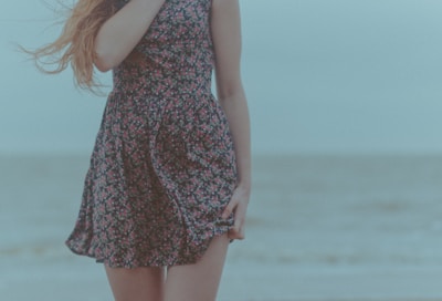 A stylish model wearing a flowing linen dress with subtle sea animal patterns, standing by the sea.