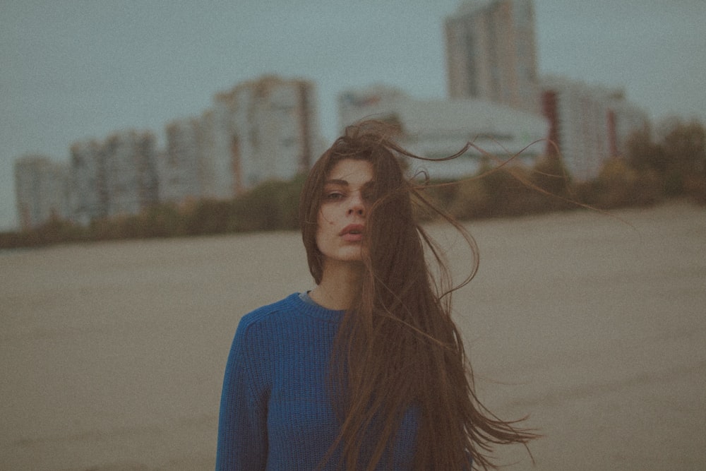 woman in blue turtleneck sweater standing on brown field during daytime