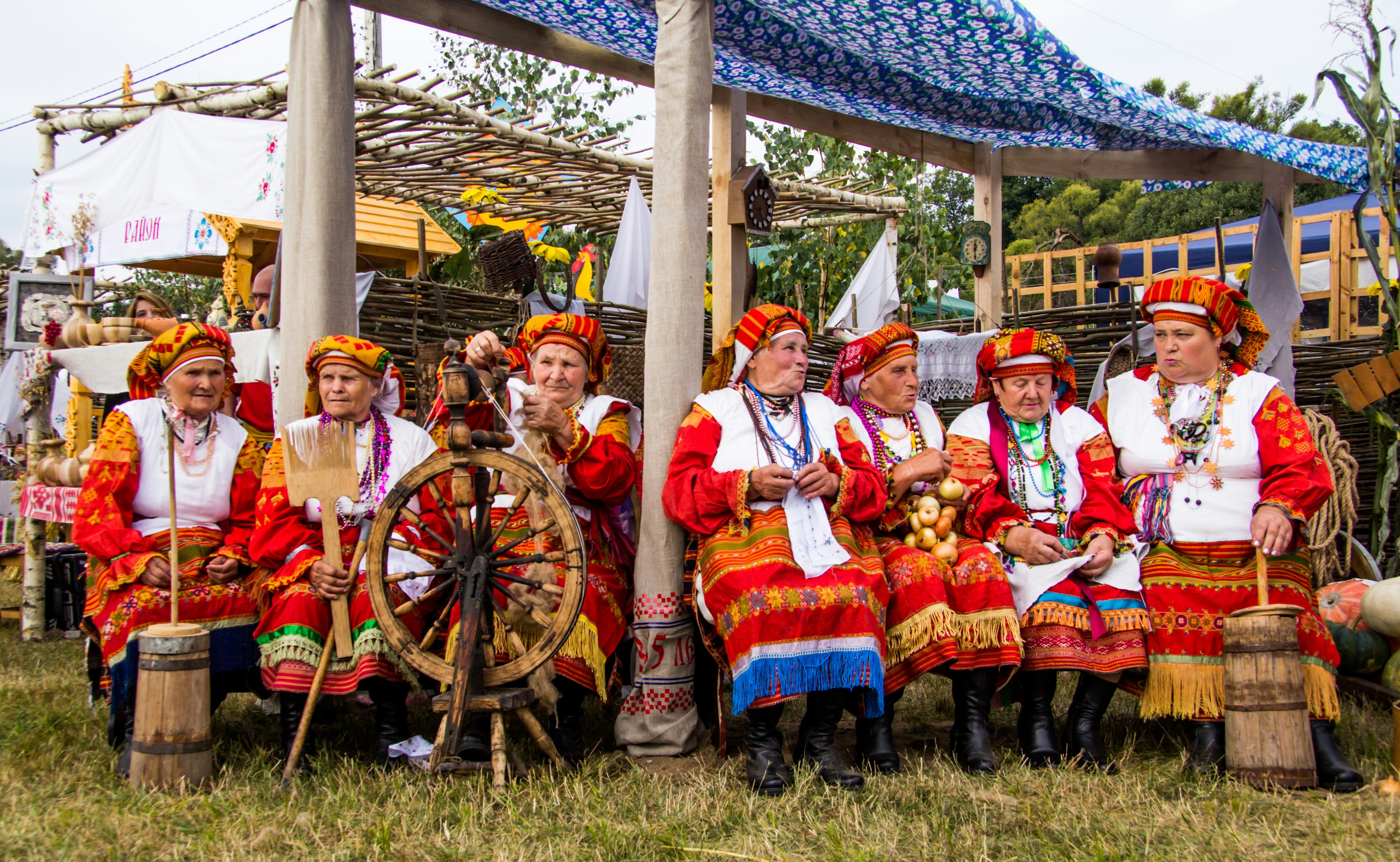 people in traditional dress sitting on green grass field during daytime