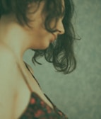 Elegant side profile showcasing silky black hair extensions styled in loose waves against a dark background.