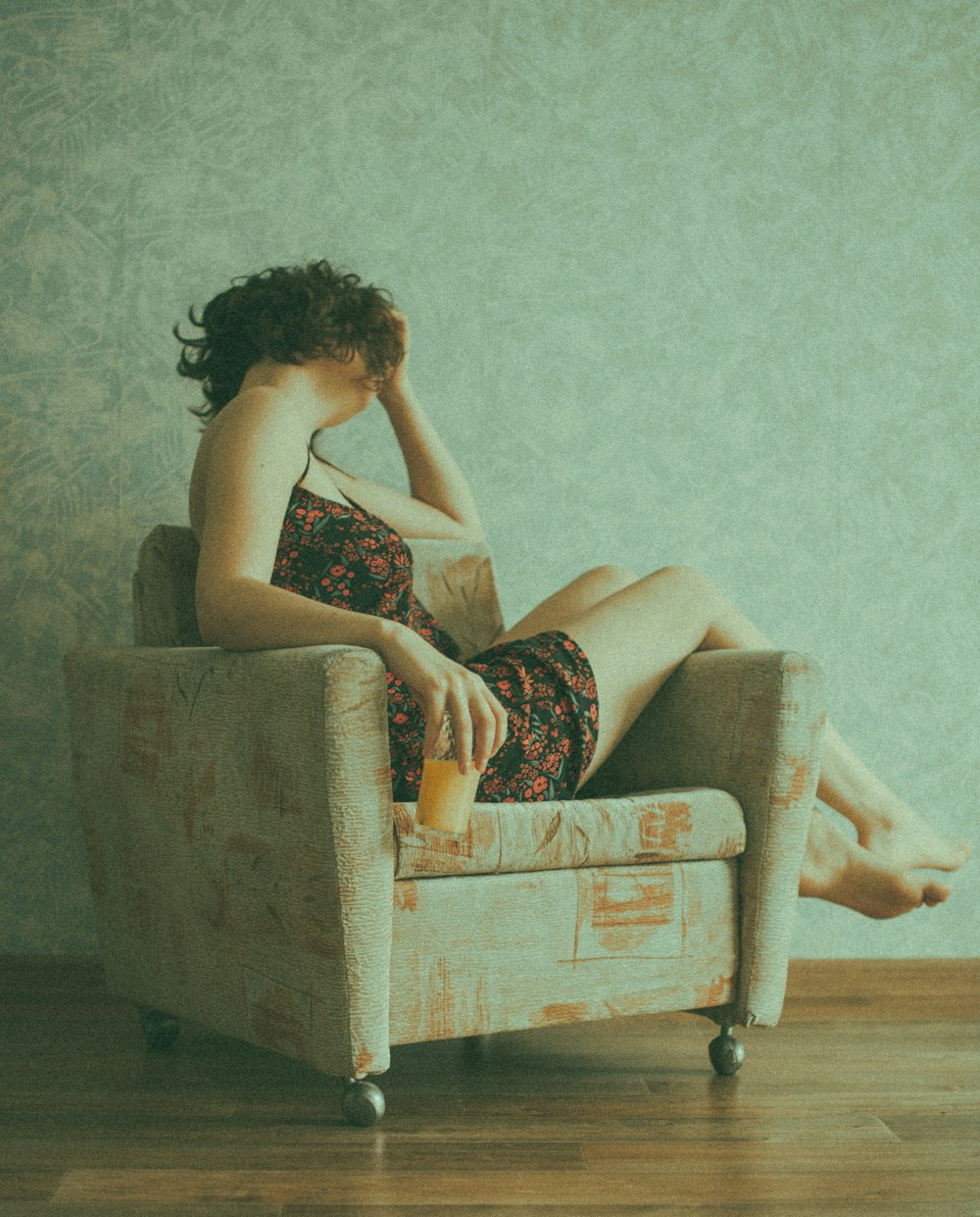 woman in black and red floral dress sitting on brown sofa chair