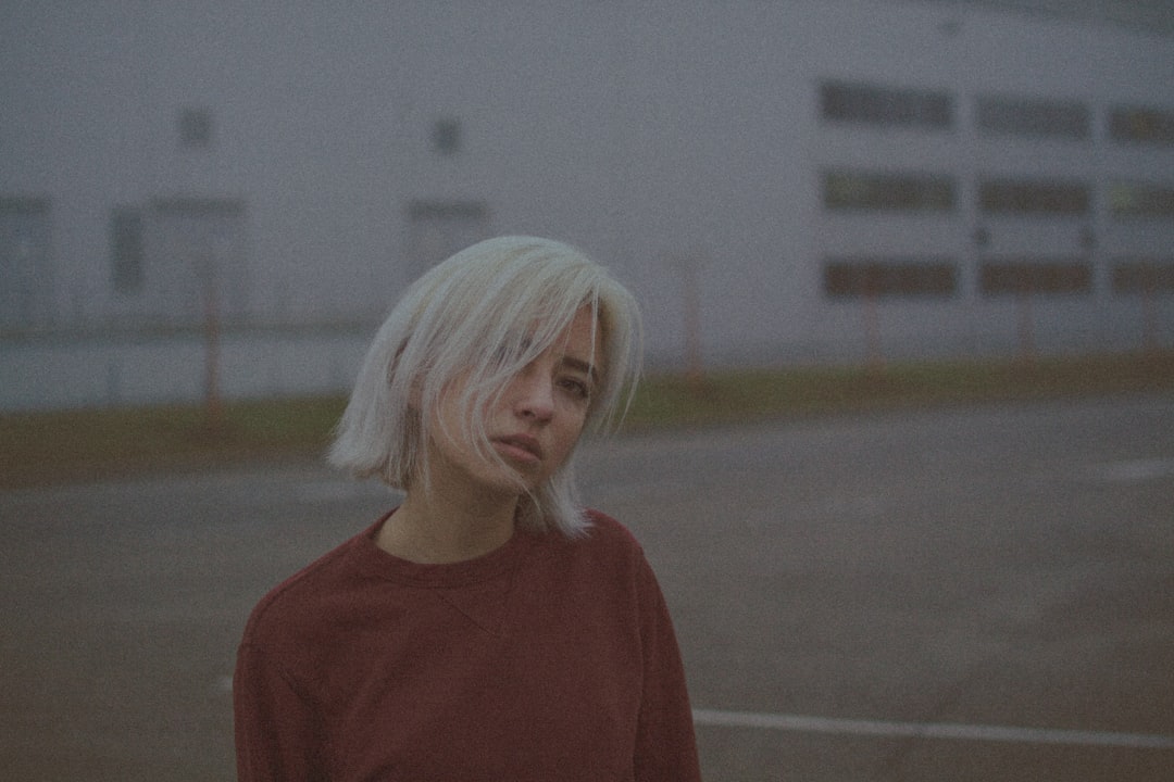 woman in red crew neck shirt standing on gray concrete floor during daytime