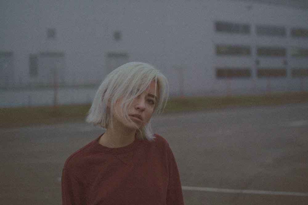 woman in red crew neck shirt standing on gray concrete floor during daytime