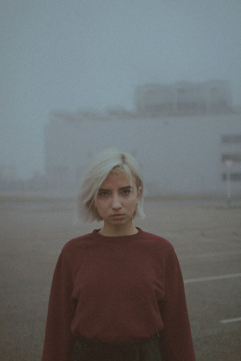 woman in red crew neck shirt standing on gray sand during daytime