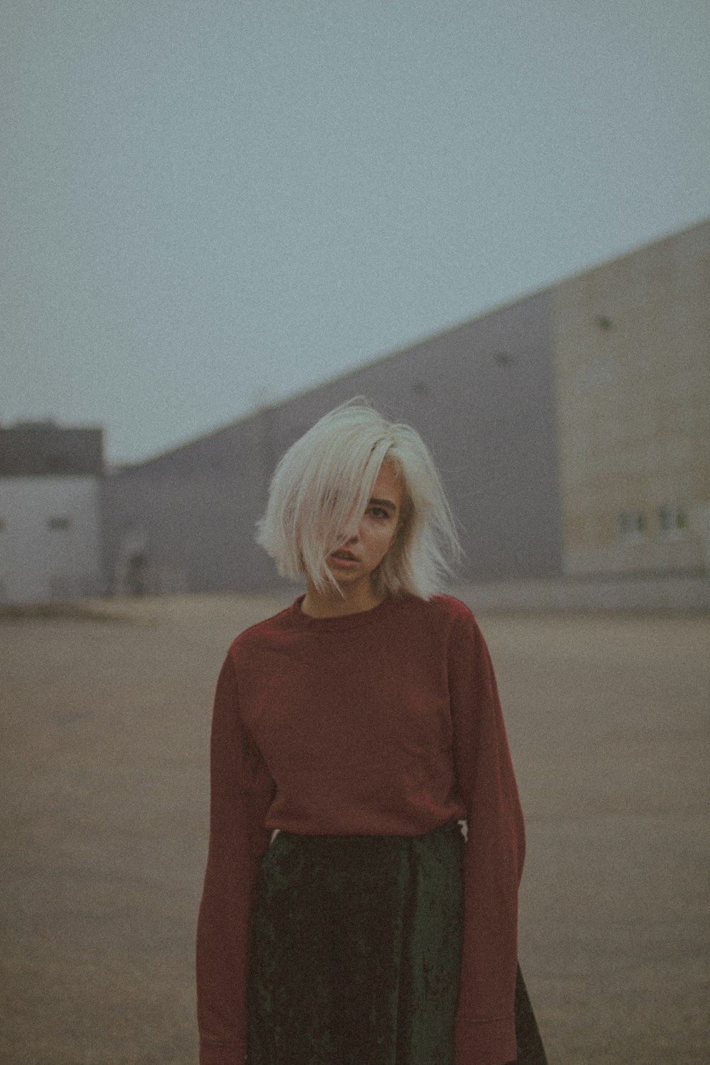 woman in red long sleeve shirt standing on brown field during daytime