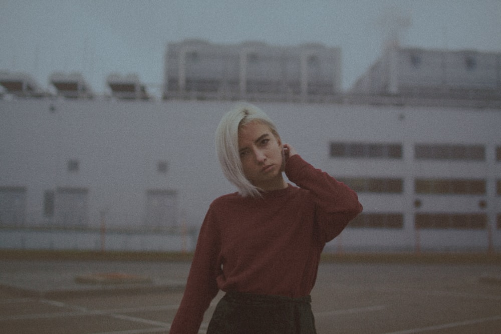 woman in red long sleeve shirt standing on gray concrete road during daytime