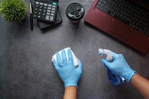une femme avec gants bleu nettoyant un bureau