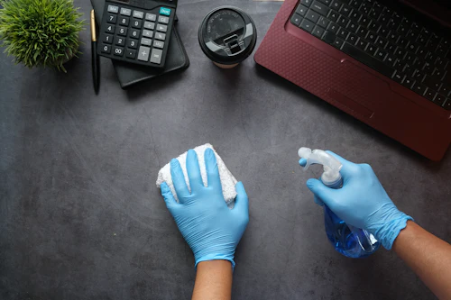 Cleaning operative wiping down an office desk
